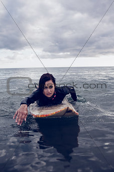Woman swimming over surfboard in water