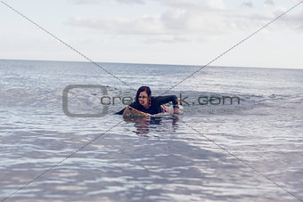 Young woman swimming over surfboard in water