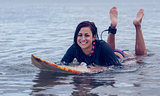 Smiling woman swimming over surfboard in water