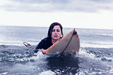 Portrait of a woman swimming over surfboard in water