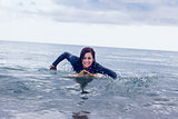 Smiling woman swimming over surfboard in water