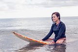 Beautiful woman sitting on surfboard in water