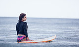 Rear view of a woman with surfboard in water