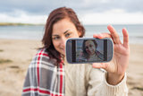 Woman self photographing with smartphone on beach