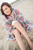 Smiling woman covered with blanket at beach