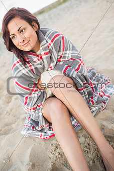 Smiling woman covered with blanket at beach