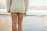 Mid section of a woman in sweater standing on beach