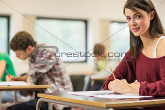 Female student with others writing notes in the classroom