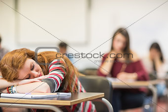 Blurred students in the classroom with one asleep girl
