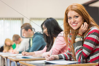 Female student with others writing notes in classroom