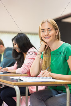 Student with others writing notes in classroom
