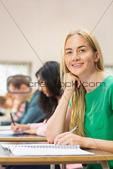 Female student with others writing notes in classroom