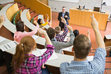 Students raising hands with teacher in the lecture hall