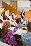 Students raising hands with a teacher in the lecture hall