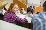 Smiling female with students and teacher in lecture hall