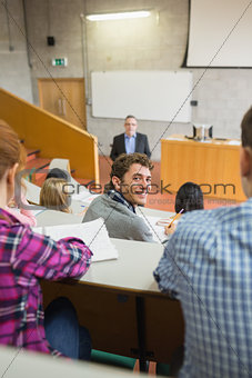Smiling male with students and teacher at lecture hall