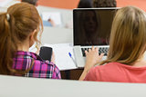 Females using laptop and cellphone in lecture hall