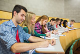 Students writing notes in a row at lecture hall
