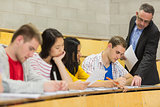 Teacher with students writing notes in lecture hall