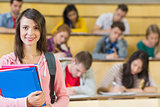 Smiling female with students sitting at lecture hall