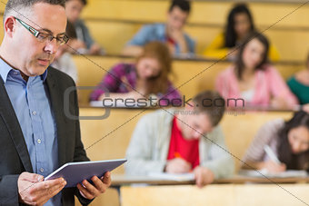 Teacher using tablet PC with students at lecture hall