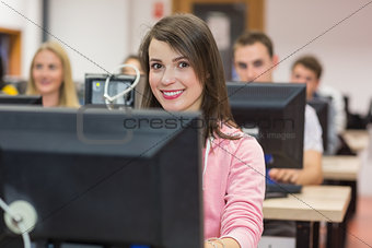 Smiling female student with others in the computer room
