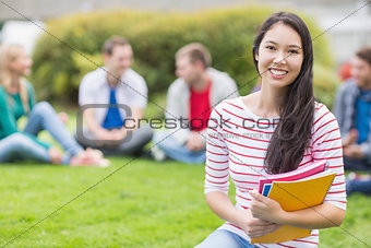 Smiling college student with blurred friends in the park