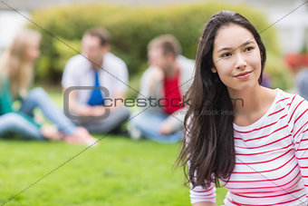 Smiling young college student with blurred friends in park