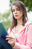 Serious college girl using tablet PC outdoors