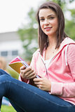 Smiling young college student with books in the park