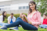 Smiling college student with blurred friends sitting in park