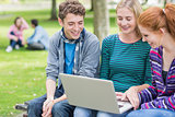 Young college students using laptop in park