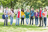 College students with bags and books standing in park