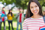 Close up of college girl with blurred students in park