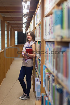 Female student standing against bookshelf in the library