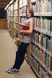 Female student leaning against bookshelf in the library