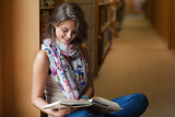 Female student reading a book in the library aisle