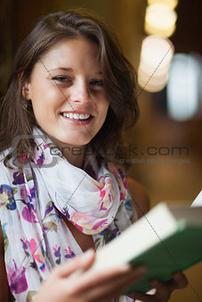 Portrait of a beautiful smiling female holding a book