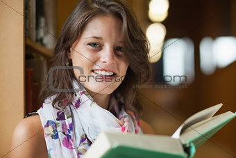 Close up portrait of a beautiful smiling female holding a book