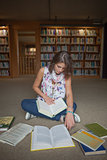 Female student sitting with books on the library floor