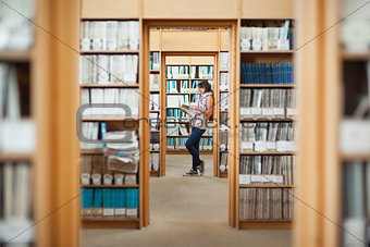 Side view of a female student reading a book in library