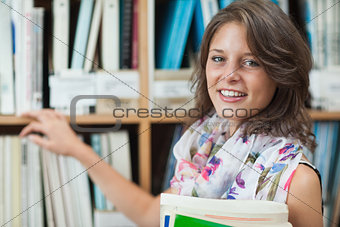 Close up portrait of a smiling female student against bookshelf in the library