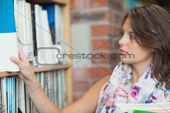 Gemale student selecting book from the shelf in library