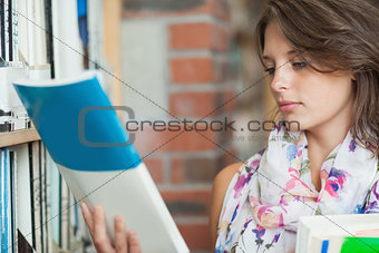 Female student with books by the shelf in library