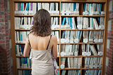 Rear view of a student at bookshelf in the library