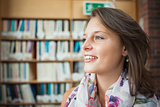 Smiling female student against bookshelf in library