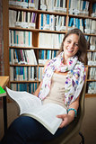 Happy female student with a book in the library