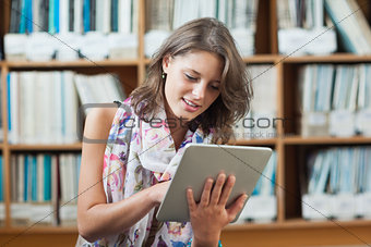 Student using tablet PC against bookshelf in library