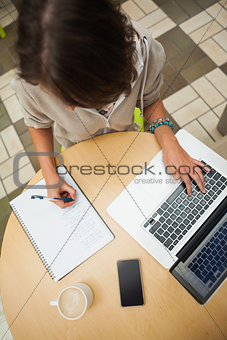 Student doing homework by laptop at cafeteria table
