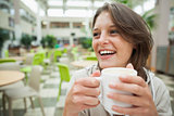 Cheerful student drinking coffee in the cafeteria